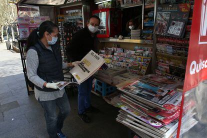 Una mujer compra un periódico, en un quiosco de la calle Toledo, en Madrid, el 15 de marzo.