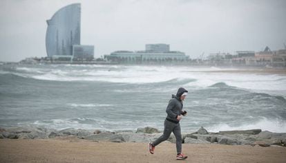Un hombre corre en un espigón de la Barceloneta durante el temporal.