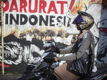 Una motorista delante de uno de los murales de X-Go, en Surabaya.