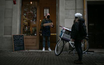 Jordi Arias, de la tienda Bebe-te, entrega un paquete a una mensajera de Les Mercedes.