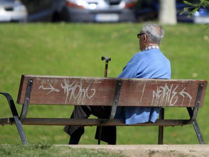 Un hombre sentado en el banco de un parque.