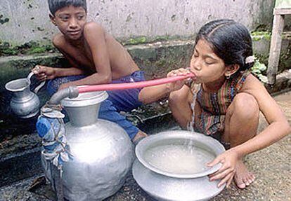 Una niña bebe con una goma de un caño público en Daca, capital de Bangladesh, en 1996.