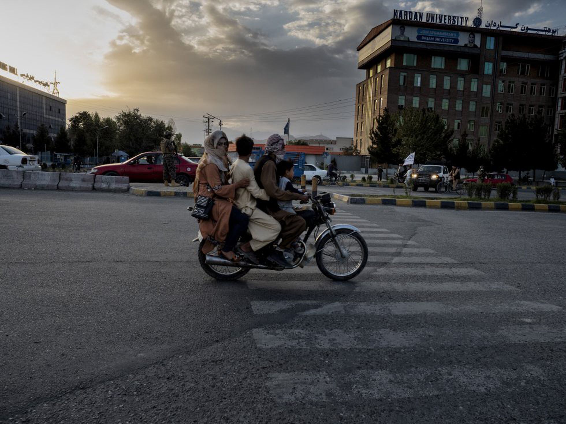Una familia afgana pasa en moto por una calle de Kabul cerca de un puesto de control de los talibanes.
