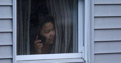 Una mujer mira por la ventana de su casa durante la busqueda policial