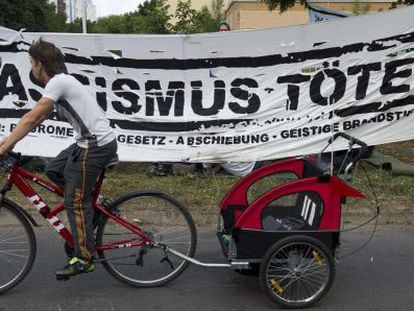 Un vecino pasa por una pancarta que dice &quot;El racismo mata&quot; montada delante del nuevo centro de refugiados en Berl&iacute;n este mi&eacute;rcoles.