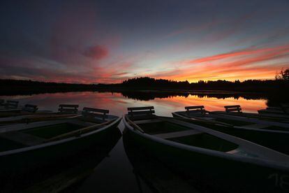 Varios botes permanecen amarrados en el lago Elbsee durante una puesta de sol en Aitrang (Alemania).