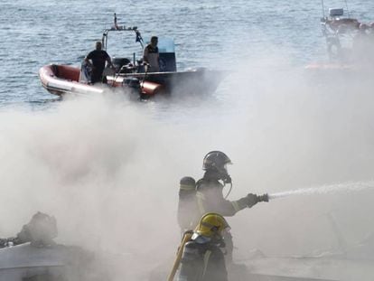 Los bomberos y equipos de rescate traban en la zona donde se incendió el catamarán en O Grove.