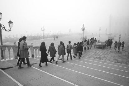 Un grupo de turistas se dirige a la Plaza de San Marcos caminando por el paseo a orillas del Gran Canal.