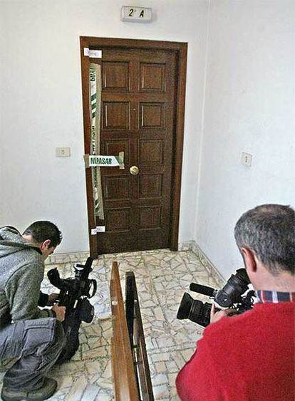 Dos reporteros de televisión graban en la puerta del domicilio donde se ha cometido el crimen.