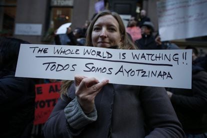 Una activista sostiene una pancarta en inglés que dice: "El mundo entero está mirando: Todos somos Ayotzinapa" en una manifestación en protesta por la desaparición de 43 estudiantes de Ayotzinapa frente al consulado de Mexico en Nueva York (EE.UU.). Edificios públicos, bancos y negocios del centro de la capital mexicana amanecieron hoy resguardados con vallas metálicas por las marchas que se llevarán a cabo.