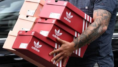 Un hombre carga con cajas de zapatillas Adidas tras salir de una tienda de la marca en Berlin, Alemania. 