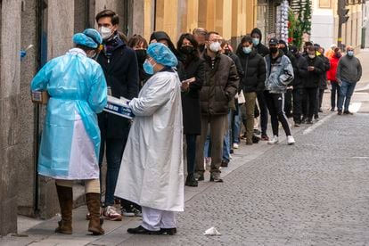 Personal sanitario atiende a personas haciendo cola para una PCR frente al centro de salud Universidad en Malasaña (Madrid).