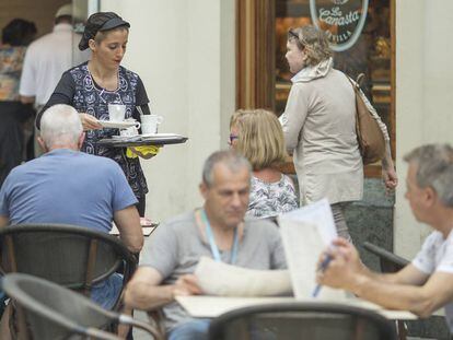 Una camarera sirve una mesa en una cafetería cétrica de Sevilla