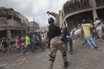 Un policía haitiano trata de dispersar a un grupo de saqueadores en el centro de la capital.
