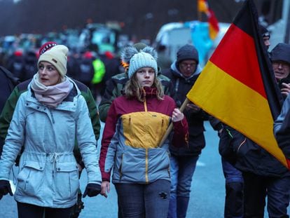 Una persona sostiene una bandera alemana mientras los agricultores protestan contra el recorte de los subsidios fiscales a los vehículos en Berlín