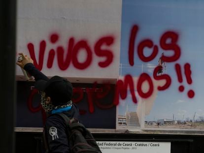 Un manifestante en el octavo aniversario de la desaparición de los normalistas pinta por encima de una fotografía, el 26 de septiembre de 2022 en Ciudad de México.