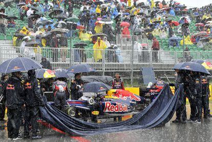 Los mecánicos de Red Bull trabajan en el coche de Vettel mientras arrecia la lluvia.