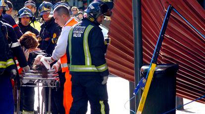 Bomberos y sanitarios atienden a uno de los heridos en la calle de la Paz de Valencia por la caída de una plancha de metal.