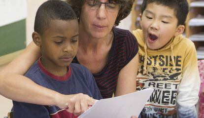 Una maestra y dos ni&ntilde;os inmigrantes en un aula de clase de catal&aacute;n. 