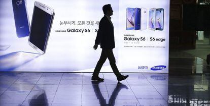 Un hombre camina junto a un cartel publicitario de Samsung.