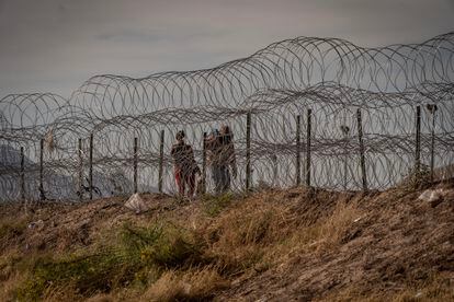 Unos migrantes caminan junto a una alambrada en la frontera con El Paso. 