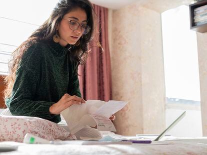 Imagen de archivo de una mujer revisando documentos y haciendo cálculos en su computadora.