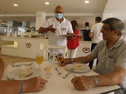 Un camarero atiende a dos clientes en un hotel de Riu en Baleares 