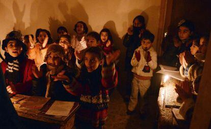 Un grupo de ni&ntilde;os sirios atiende una clase con velas ante los cortes de electricidad en Kadi Askar, al norte de Alepo.
