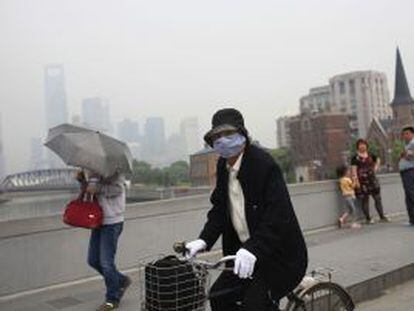 La contaminaci&oacute;n de Shanghai obliga a una ciclista a usar mascarilla.