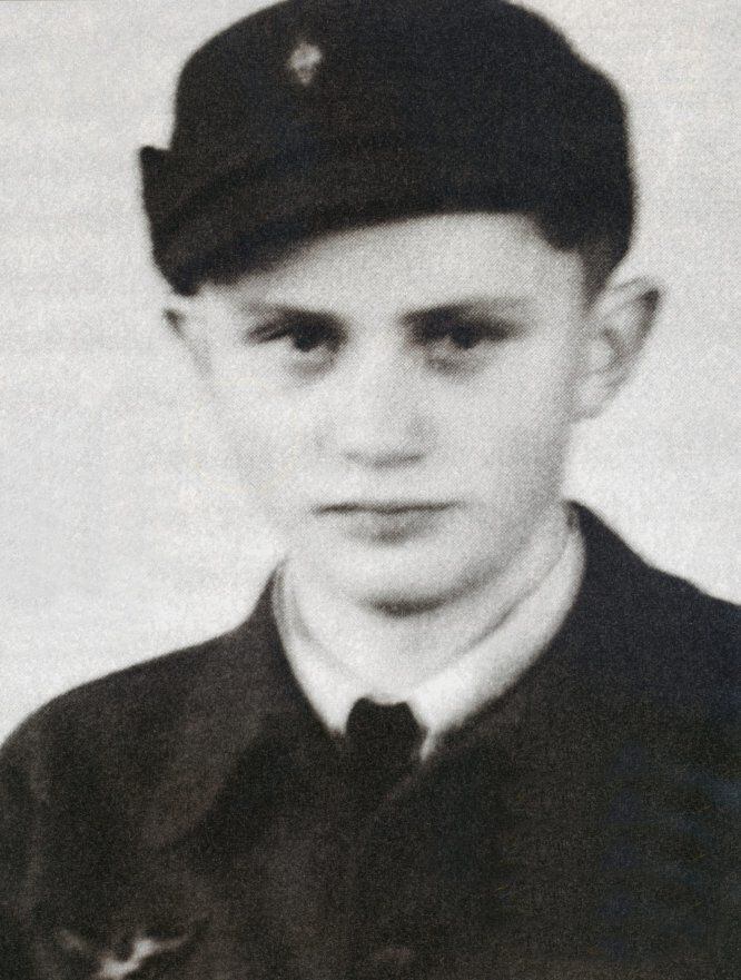 Joseph Ratzinger, en Múnich, con 16 años, vestido con el uniforme militar. En 1941, con 14 años, ingresa en las juventudes hitlerianas (algo obligatorio en ese momento) cuando estaba en el seminario.  En 1943 es movilizado y destinado a una batería antiaérea (que le llevará a Múnich, Innsbruck y Gilching). En 1944, aun sabiendo que los desertores eran fusilados, abandona su puesto y regresa a casa, donde es detenido por los estadounidenses y enviado a un campo de prisioneros hasta su liberación, el 19 de junio de 1945. Su hermano, movilizado también y del que no tenía noticias, regresa un mes después. Tras ser elegido Papa, su paso por las Hitlerjugend fue objeto de polémica. Para atajarla, Ratzinger impulsó una investigación que determinaría que su paso por el ejército nazi no fue voluntario.