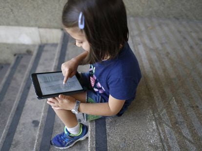 Una niña lee un libro en una tableta.