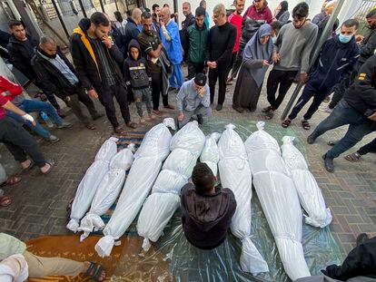 Varias personas rodean los cuerpos tapados de varias víctimas (algunos niños), al sur de la Franja de Gaza, tras reanudarse el intercambio de fuego entre Israel y Hamás.