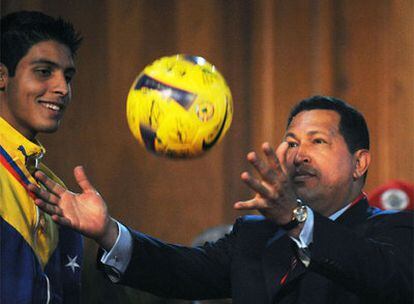 Chávez juega con un balón ante el futbolista de la selección sub 20 Rafael Romo durante una ceremonia en el palacio de Miraflores.