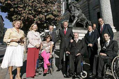 El ministro de Trabajo y Asuntos Sociales, Jesús Caldera, posa junto a tres discapacitados que se beneficiarán de la ley de Dependencia.