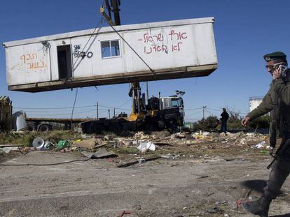 Un policía fronterizo israelí pasa junto a una casa prefabricada, mientras es retirada, este martes durante la demolición del asentamiento ilegal judío de Amoná, en Cisjordania.