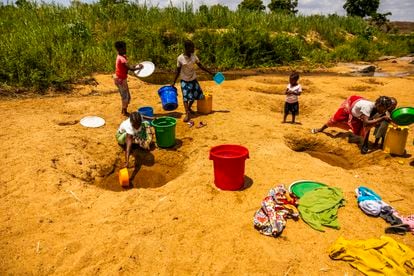 Ella y sus hermanos llenan baldes grandes con el agua que recogen en charcos que se forman en los márgenes del río.