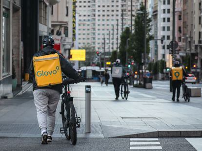 Dos repartidores de Glovo y otro de Deliveroo, en la Gran Vía de Madrid.