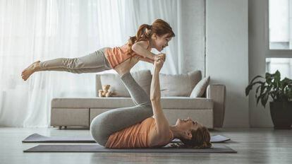 Una madre y su hija hacen ejercicio en su casa. 