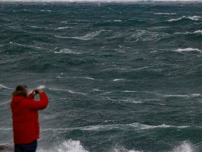 Un hombre fotografía el fuerte oleaje que azota el litoral de Muxía, en la Costa da Morte (A Coruña)