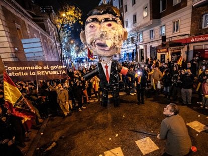 Un hombre se dispone a golpear un muñeco con la figura de Pedro Sánchez en la protesta cerca de la calle de Ferraz, en Madrid, en Nochevieja.
