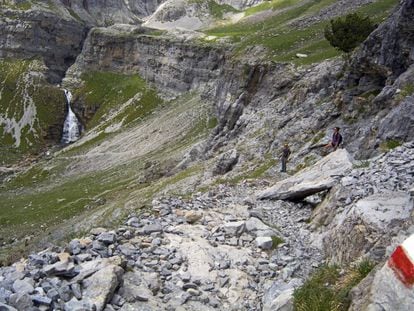 Señal roja y blanca de la ruta GR 11 a su paso por el valle de Ordesa (Huesca). Al fondo, la cascada Cola de Caballo.