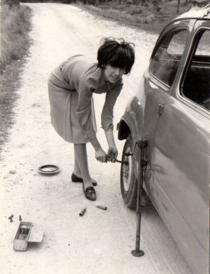 Una mujer arregla el pinchazo en una rueda de su coche en 1966.
