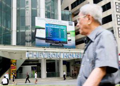 Un hombre camina junto a una pantalla que muestra la información de la bolsa en Singapur. EFE/Archivo