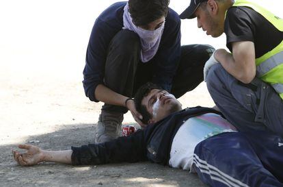 Dos compañeros ayudan a un hombre herido en la frontera griega, al norte de Idomeni.