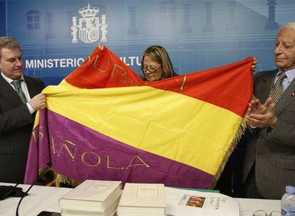 Linda Gregory muestra la bandera a César Antonio Molina y José Dalmau.
