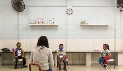 Una maestra da clase a tres de sus alumnos, todos separados por la distancia mínima de seguridad, en una escuela de educación primaria de São Paulo, en Brasil.