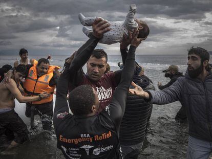 Un voluntario sostiene a un bebé en las costas griegas de Lesbos.