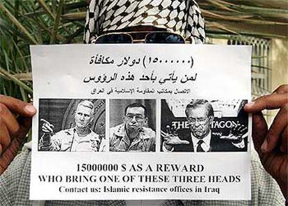 Un insurgente muestra un cartel que ofrece una recompensa por Rumsfeld y los generales Sánchez y Kimmitt.