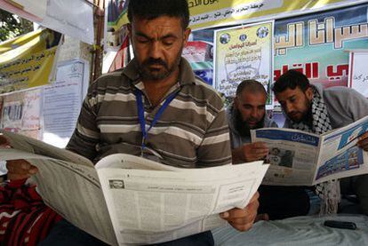 Tres palestinos leen en los periódicos la lista de los primeros presos excarcelados por Israel, ayer en Gaza.