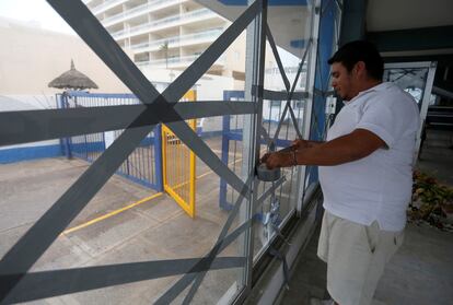 Un hombre protege los vidrios de un hotel ante el peligro de que estos se rompan por los fuertes vientos de 'Orlene', en Mazatlán, el 2 de octubre de 2022. 